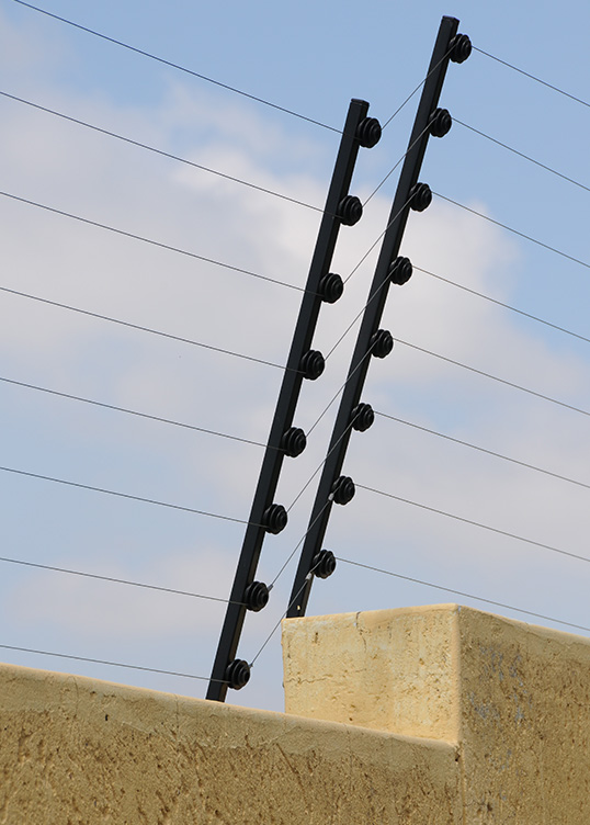 Potelets et fils de clôture électrique posés sur un mur
